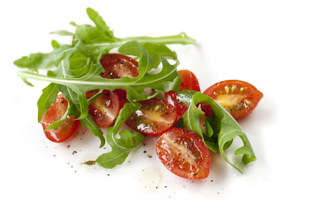 Cherry tomatoes and arugula, isolated on white.  Baby roma or plum variety.の写真素材