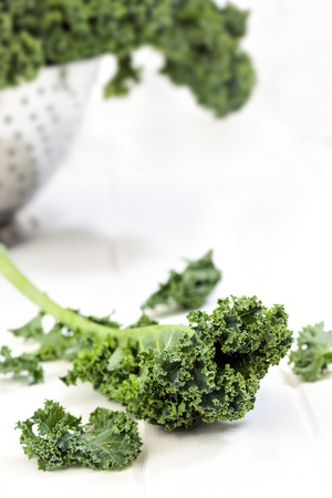 Kale leaves on bench, with colander behind.の写真素材