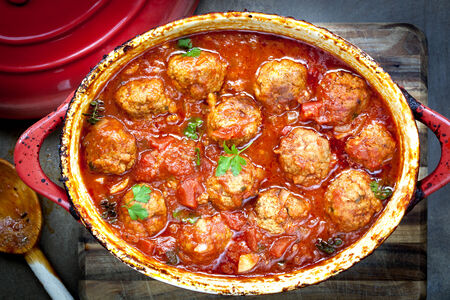 Meatballs casserole in red iron crock pot.の写真素材