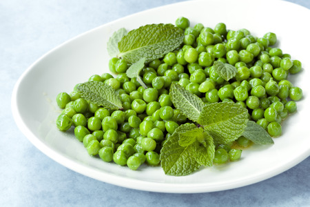 Peas with mint on a white plate over blue.の写真素材