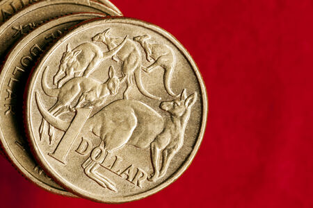 Australian money.  One dollar coins over red background.  Overhead view.