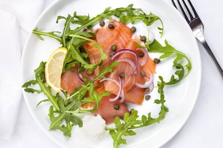 Smoked salmon salad with red onion, capers and arugula. Overhead view.の写真素材