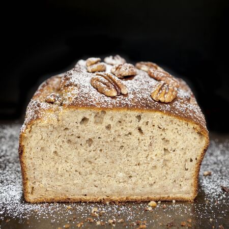 Banana bread with pecans, straight from the oven.  Cut loaf, over black.