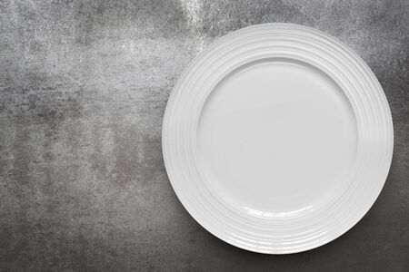 Empty white plate over gray slate. Top view, with copy space.の写真素材