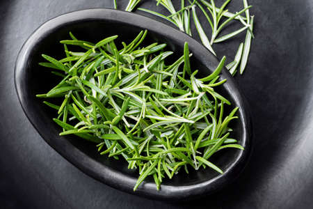 Rosemary, top view in rustic black bowl.  Fresh herbs.の写真素材