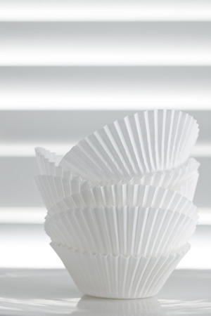 Stack of empty cupcake cases over white slat background.の写真素材