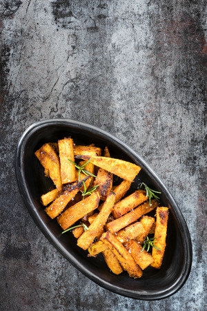Sweet potato fries in black bowl, top view over slate.の写真素材