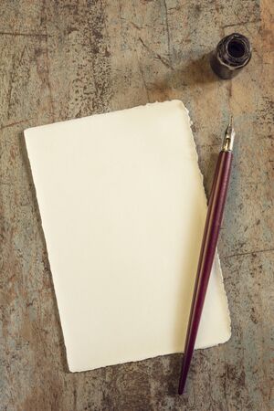 Nib pen and inkwell with blank vintage paper.  Top view, on rustic timber.の写真素材