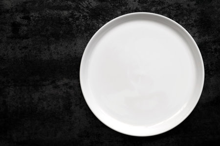 Empty white plate over black slate.の写真素材