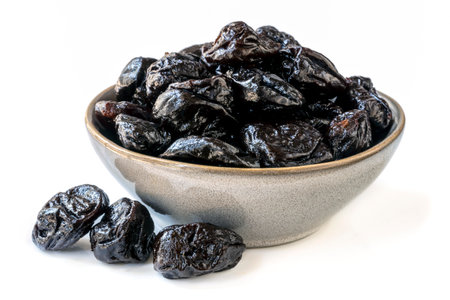 Bowl of fresh juicy pitted prunes over white background.の写真素材