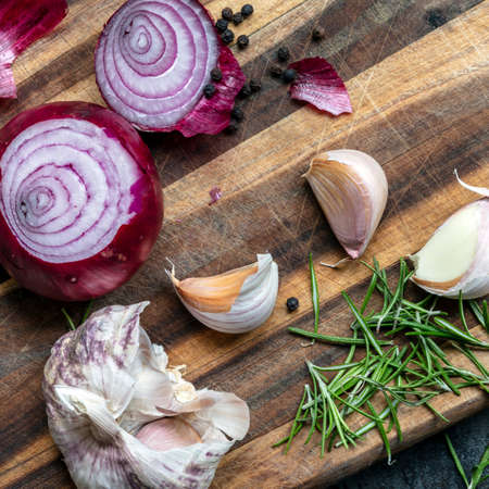 Food preparation.  Garlic, red onions, peppercorns and rosemary on chopping board.  Top view.の写真素材