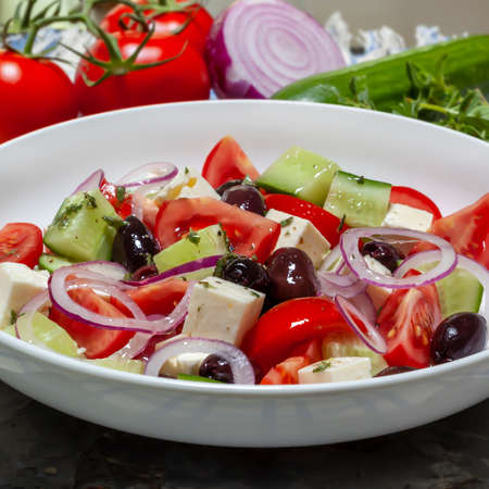 Greek salad in white bowl, with ingredients behind.  Delicious Mediterranean food.の写真素材