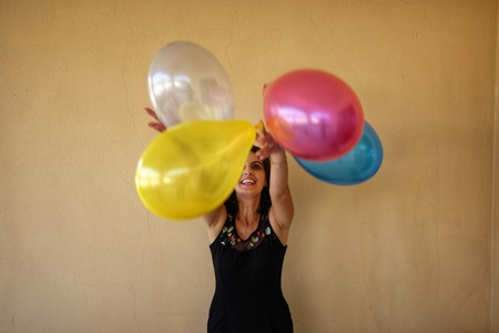 woman throws colored balloons into the airの写真素材