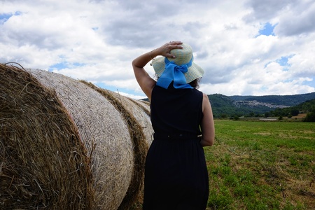woman with hat in the field with round balesの写真素材