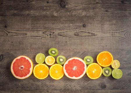 Slices of fresh fruit on a brown table with place for inscription