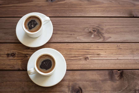 View of two cups of coffee on wooden table with place for inscriptionの写真素材