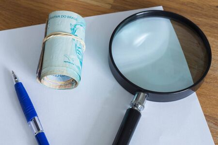 Brazilian money, reais, high nominal with a sheet of paper and a pen for calculationsの写真素材