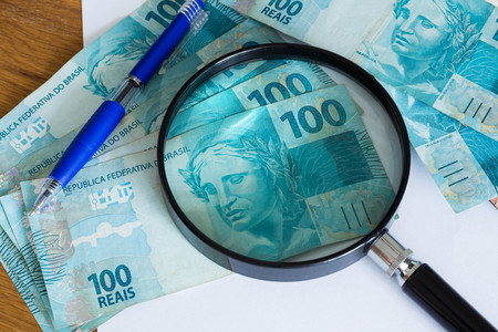 Brazilian money, reais, high nominal with a sheet of paper and a pen for calculationsの写真素材