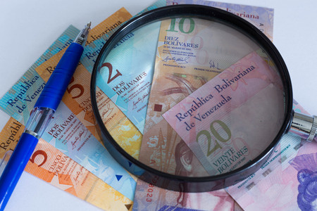 View of Venezuelan money with magnifying glass and pen / crisis concept