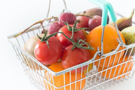 Shopping basked with fruits and vegetables on a white backgrounds / concept healthy, nutrition supporting the dietの写真素材