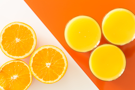 Orange juice and fruits on the white-orange glass background.の写真素材