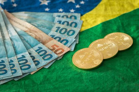 Brazilian money and bitcoins against the Brazilian flag