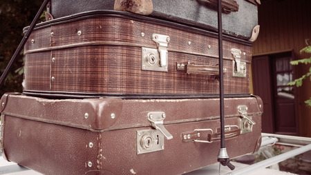 Preparations for travel. Old suitcases stacked on top of each other on the roof of a vintage carの写真素材