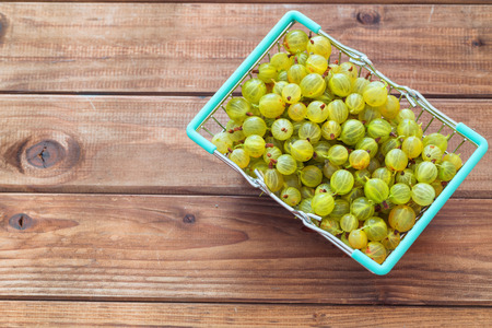 gooseberries in a shopping basket on a wooden tableの写真素材