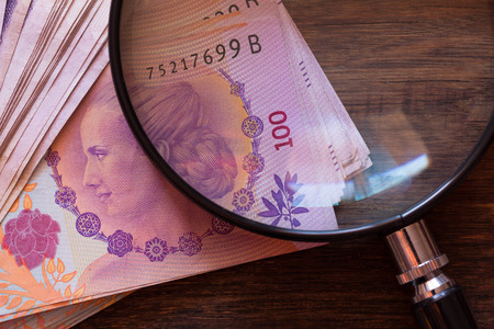 Argentine money, pesos on the table with a magnifying glass