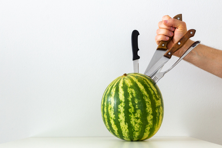 juicy whole watermelon with knifed knives and fork / conceptの写真素材