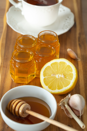tea, lemon, honey and garlic on a wooden counter, healthy and natural remedies for coldsの写真素材