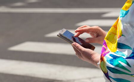 The woman, straring at the phone, crosses the streets / concept