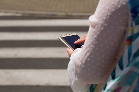 A woman at a pedestrian crossing looking at the smartphone. safety conceptの写真素材