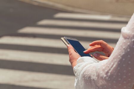 A woman at a pedestrian crossing looking at the smartphone. safety conceptの写真素材