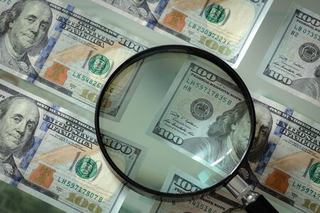 American money hundred dollar bills and magnifier on a glass backgroundの写真素材