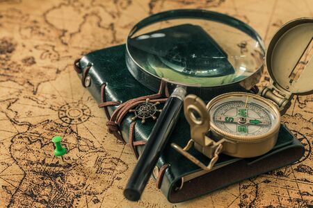 old map with compass, notebook and magnifying glass. The concept of searching for interesting places or treasures around the world.の写真素材