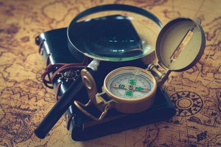 old map with compass, notebook and magnifying glass. The concept of searching for interesting places or treasures around the world.の写真素材