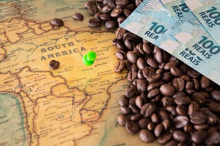 Old map of Brazil with scattered coffee beans and 100 reais banknotes, Concept of the largest coffee producer and exporter in the worldの写真素材