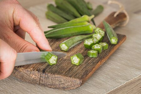 Okra cut with a knife on a chopping board in the kitchenの写真素材