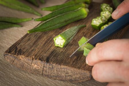 Okra cut with a knife on a chopping board in the kitchenの写真素材