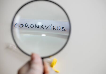 Coronovirus vial under a magnifying glass, The concept of research and finding a cure for a...