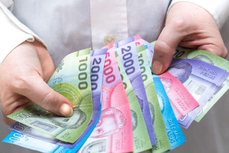 a woman holds in her hands spread out money from chile