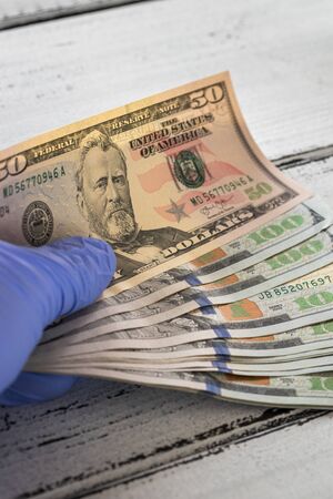 US dollars kept in rubber gloves. The concept of economy and financial threats during the Coronavirus pandemicの写真素材