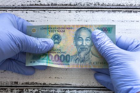 Vietnam money, Dong, banknote kept in rubber gloves. The concept of economy and financial threats during the Coronavirus pandemicの写真素材