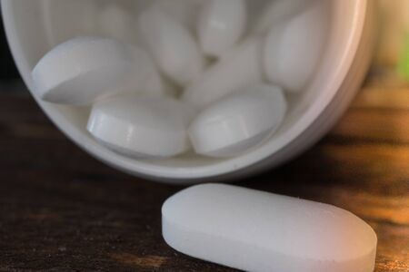 White tablets spilling out of a container. Health concept