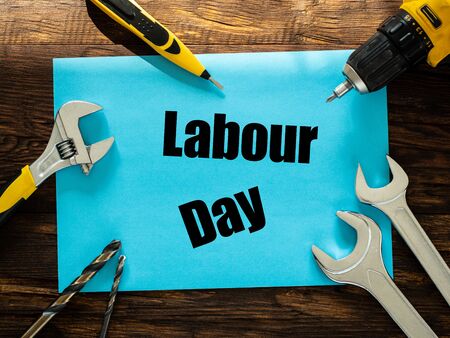 blue card lying on wooden boards between the assembly tools with the inscription "Labor Day" Concept of the holiday of working peopleの写真素材