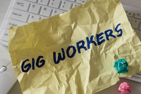 crumpled piece of paper with the hand-written "Gig Workers" lying on the computer keyboard. The concept of short-term contracts for work and poor employee protectionの写真素材