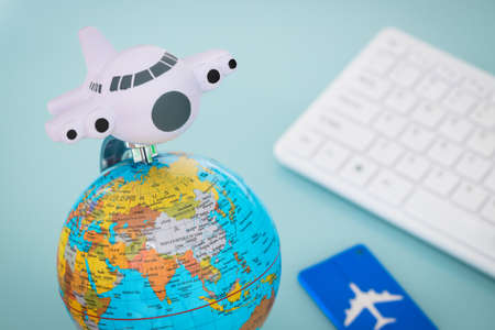 Desk with aviation and travel items. Globe, toy plane, Luggage tag, Computer keyboard, Air travel planning conceptの写真素材
