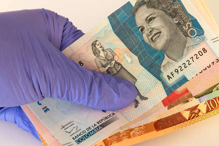 Columbian money, pesos banknotes kept in rubber gloves. The concept of economy and financial threats...