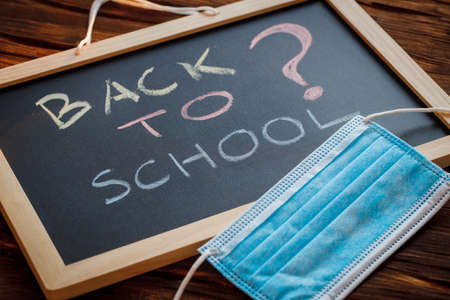 Back to School, The sign on the school board that says a question mark and an anti-virus mask. The concept of risk related to school attendance by children and young people in the timeof the coronavirus pandemicの写真素材